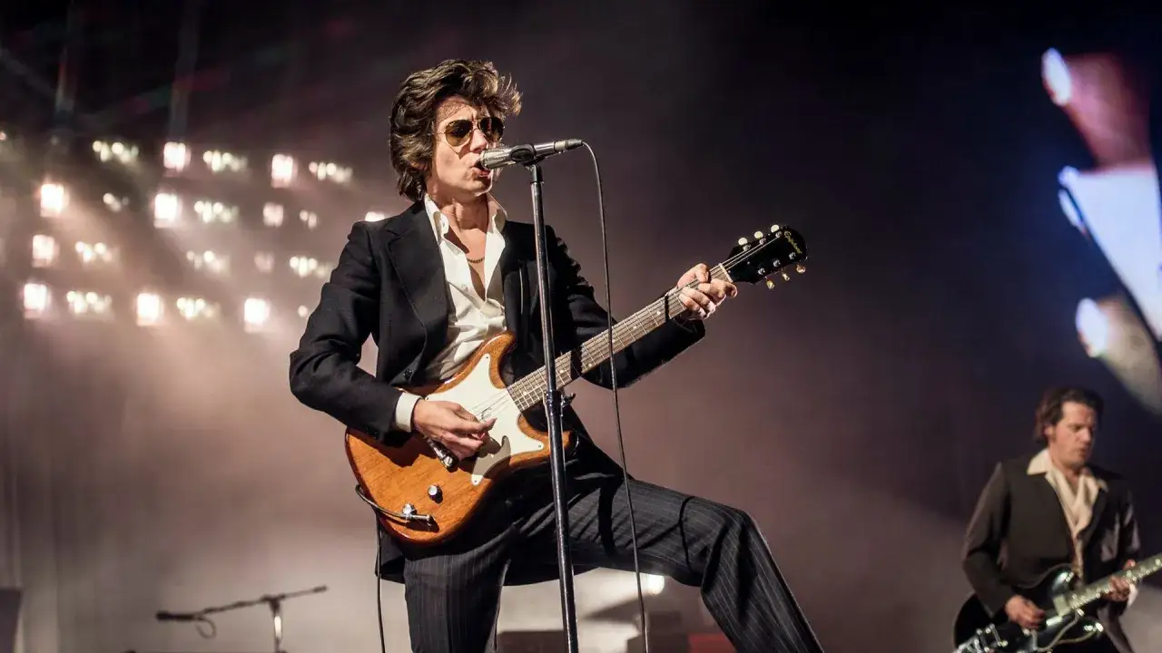 Alex Turner spelar gitarr på scenen under en konsert i Stockholm. Arctic Monkeys levererar en energisk show.