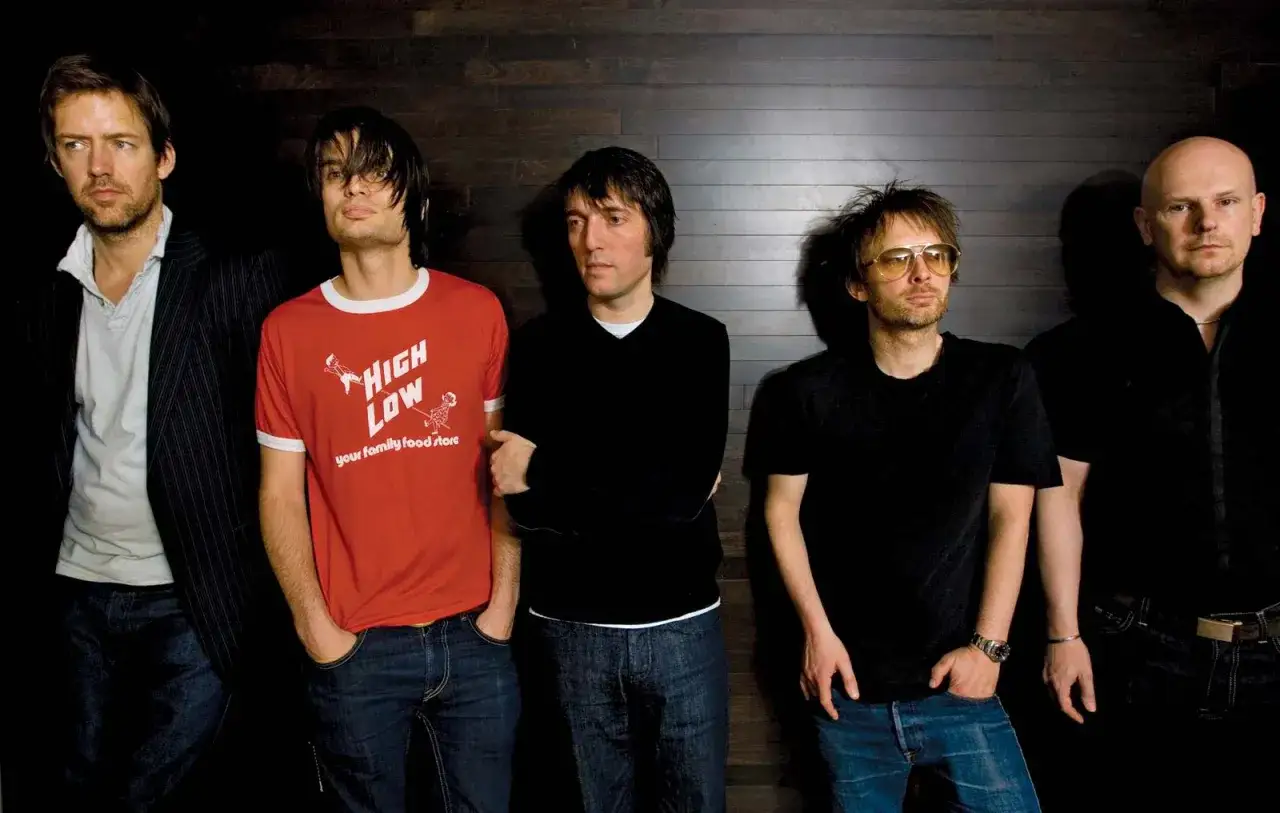 Medlemmar av Radiohead står uppradade framför en mörk trävägg. Från vänster: Ed O'Brien, Colin Greenwood, Phil Selway, Thom Yorke och Jonny Greenwood.