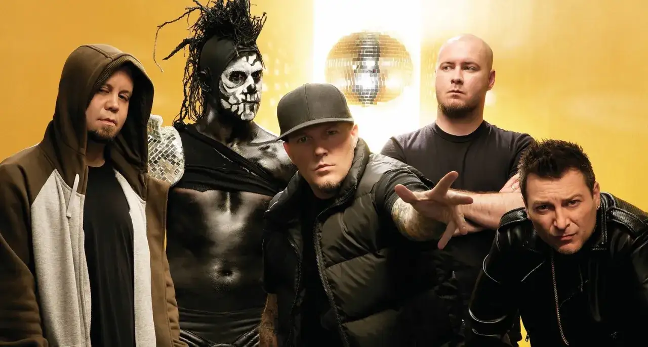 Medlemmar av Limp Bizkit poserar framför en gul bakgrund med en discokula.