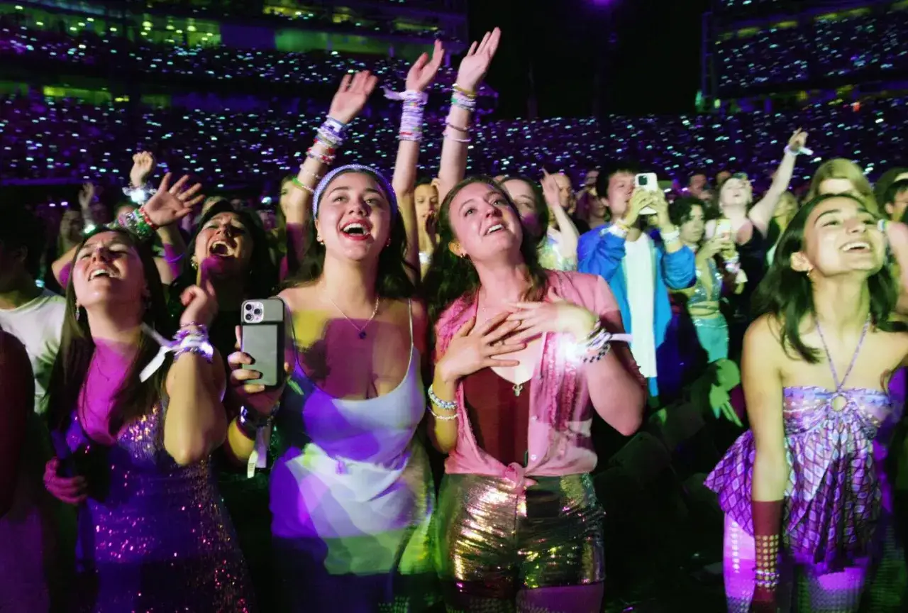 Glada fans sjunger med till taylor swift-låtar på en konsert, omgivna av tusentals ljus.