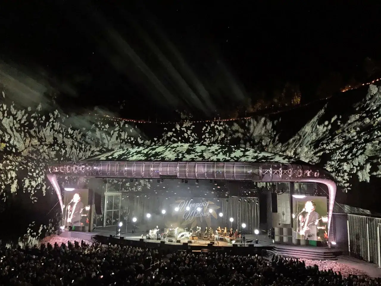 Konsert med Weeping Willows på Dalhalla. En stor publik ser bandet uppträda under en stjärnklar natt med ljusshower.