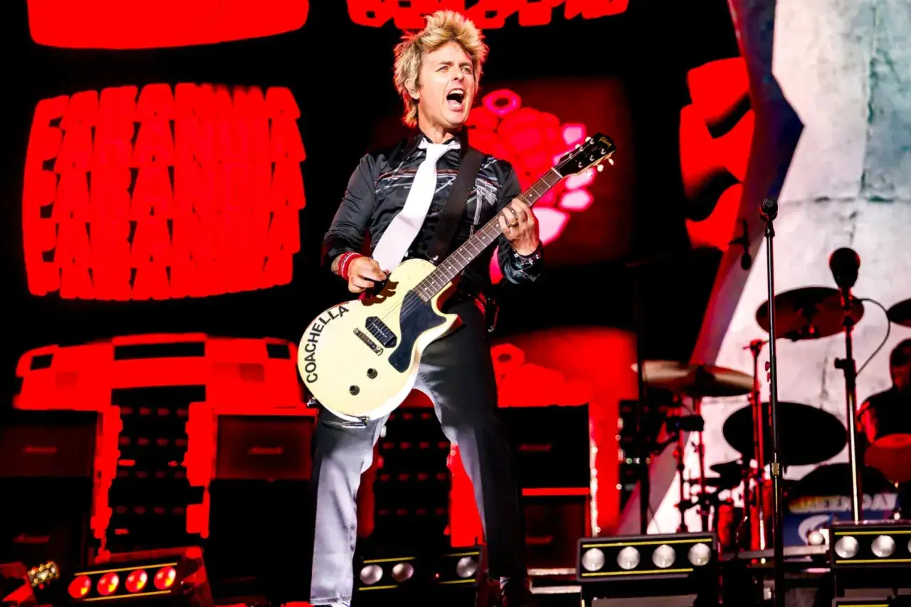 Green Day sångare, Billie Joe Armstrong, spelar gitarr på scenen under en energisk konsert.