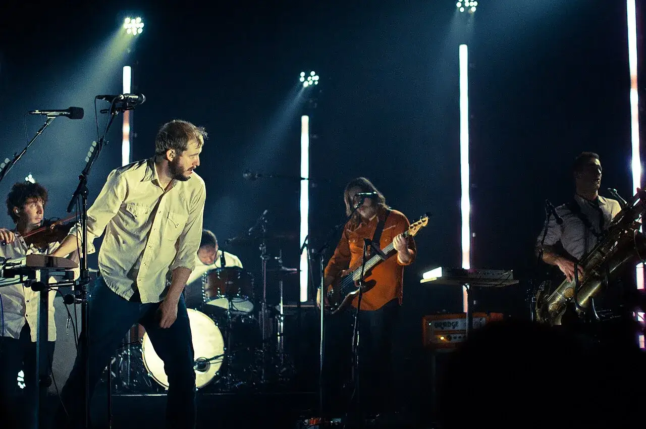 Bon Iver spelar i Sverige. Bandet uppträder på scen med musiker som spelar gitarr, saxofon och fiol.