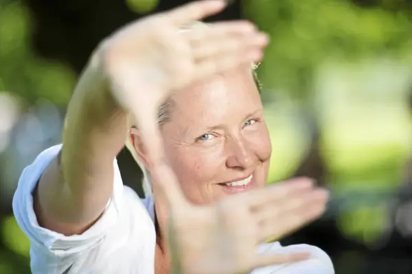 Regina Lund ler inramad av sina händer, som om hon skapar en scen för en film.