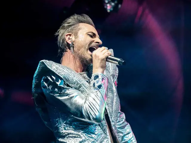Sångaren i The Ark, Ola Salo, sjunger passionerat i en glittrig silverjacka under en konsert.